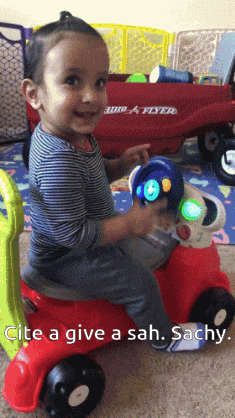 a little boy is sitting on a red toy car with the words " invite a give a sah sachy " on the bottom
