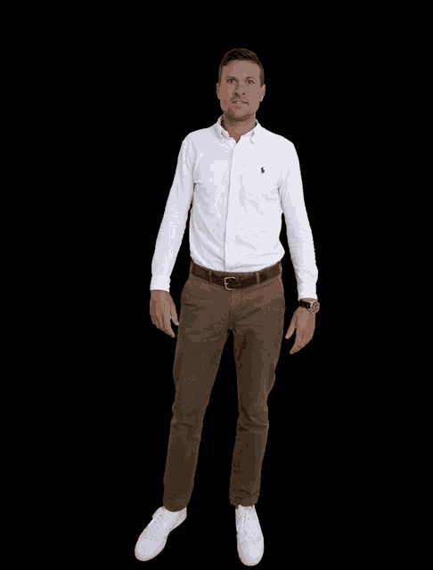 a man wearing a white shirt and brown pants is standing in front of a black background