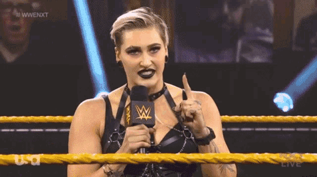 a woman in a wrestling ring holding a microphone with a w on it