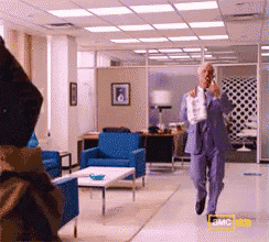a man in a blue suit is talking on a phone in an office