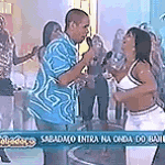 a man is singing into a microphone while a woman is dancing in front of a crowd .