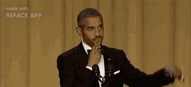 a man in a tuxedo is giving a speech on a stage .