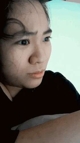a close up of a woman 's face with a blue sky behind her