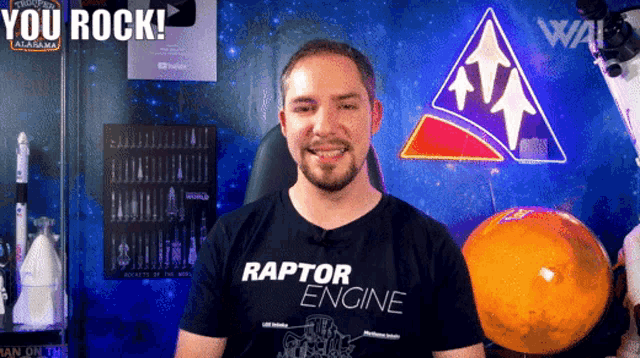 a man wearing a raptor engine t-shirt smiles