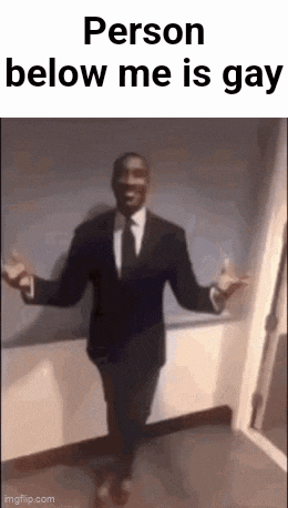 a man in a suit and tie is standing in a hallway with his arms outstretched and says person below me is gay .