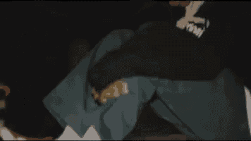 a man in a black hoodie is sitting down in the dark .