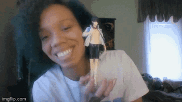a woman is smiling while holding a figurine of a person