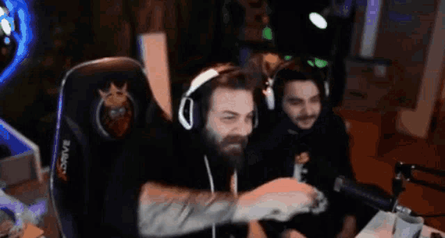 a man with a beard wearing headphones is sitting in a gaming chair