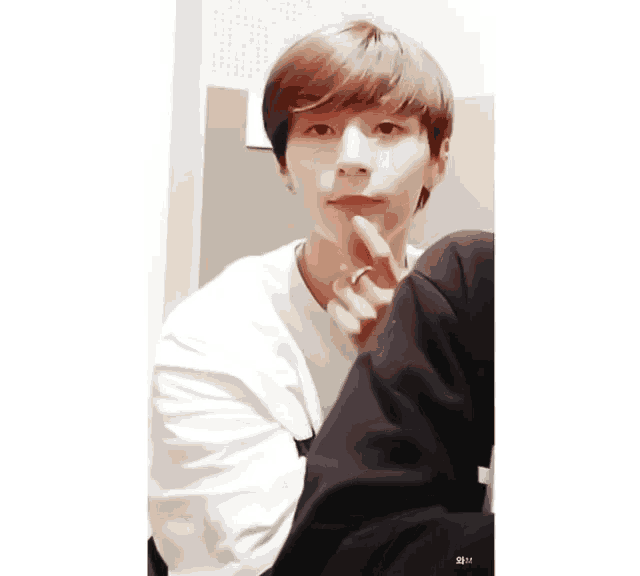 a young man in a white shirt is sticking his finger out