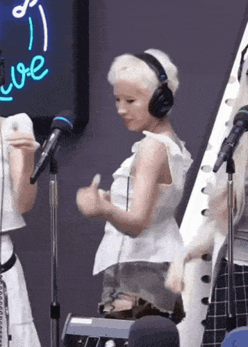 a woman wearing headphones stands in front of a microphone and a sign that says love