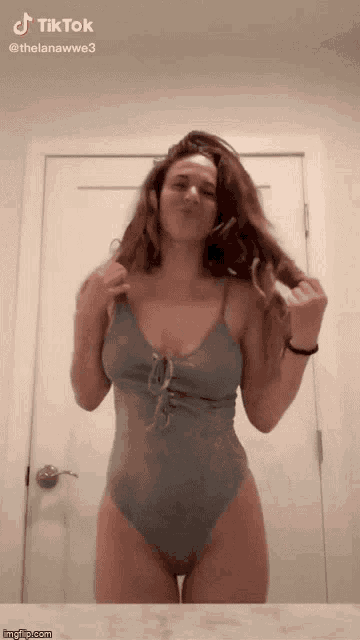 a woman in a one piece swimsuit is standing in front of a door with tiktok written on the bottom right