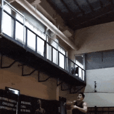 a man playing basketball in a gym with a sign that says pressure