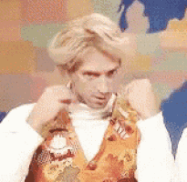 a man wearing a vest and a turtleneck is adjusting his hair .