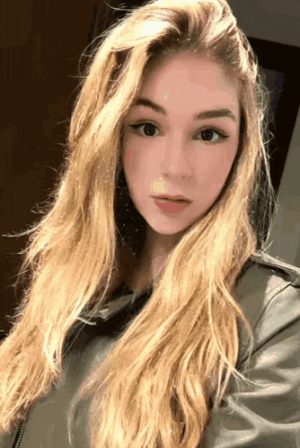 a woman with long blonde hair is wearing a black leather jacket