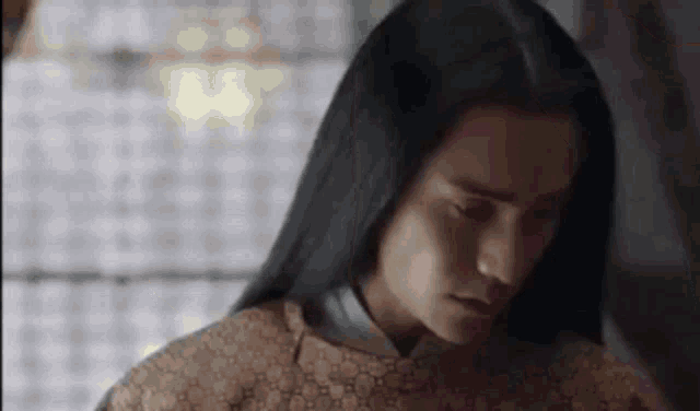 a close up of a person with long black hair wearing a sweater .