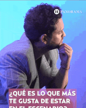 a man with a beard is sitting in front of a blue background with panorama written in white letters