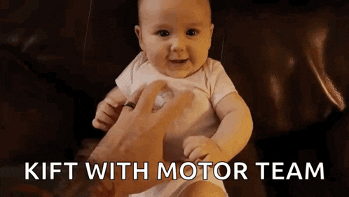 a baby is sitting on a couch with a pacifier in his mouth and a person is holding him .