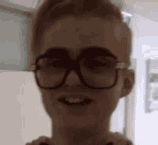 a close up of a woman wearing glasses and smiling in a room .