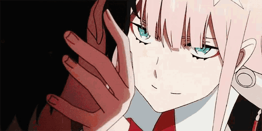 a girl with pink hair and blue eyes is touching another girl 's face with her hand