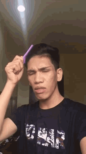 a young man wearing a black shirt with the word gap on it combs his hair