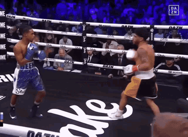 two boxers are fighting in a boxing ring with dazn written on the ring ropes