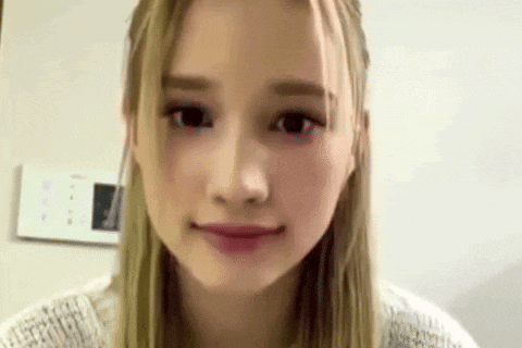 a close up of a woman 's face with long blonde hair and a white sweater .