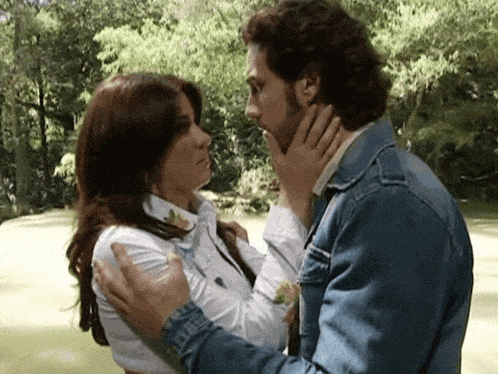 a man in a denim jacket kisses a woman on the forehead