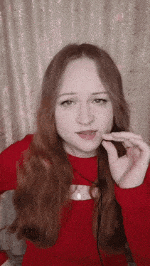 a woman with long red hair wearing a red top
