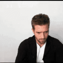a man with a beard is wearing a black jacket and tie