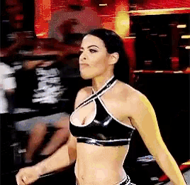 a woman is standing in a boxing ring wearing a black crop top and shorts .