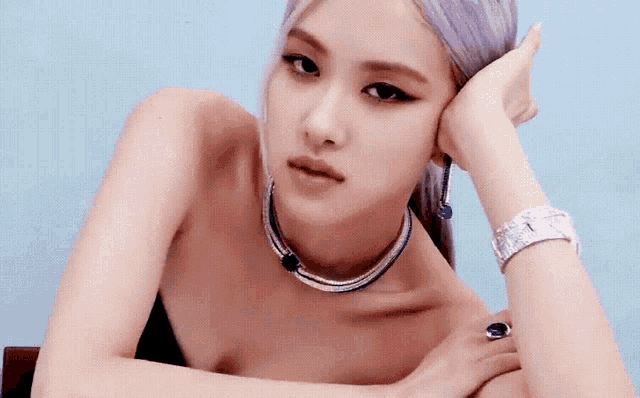 a woman with purple hair is wearing a necklace and a watch