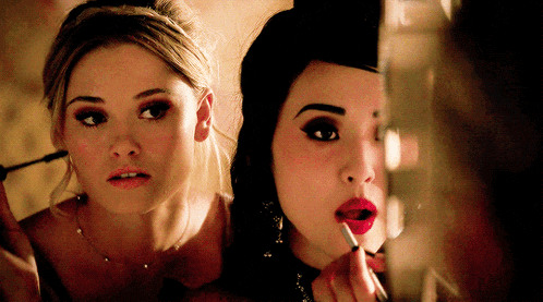 a woman is applying lipstick to another woman 's lip