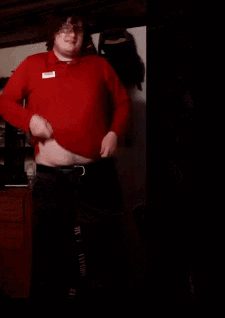 a man without a shirt is dancing in a room with a backpack hanging on the wall