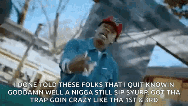 a man in a blue shirt and red hat is giving a thumbs up