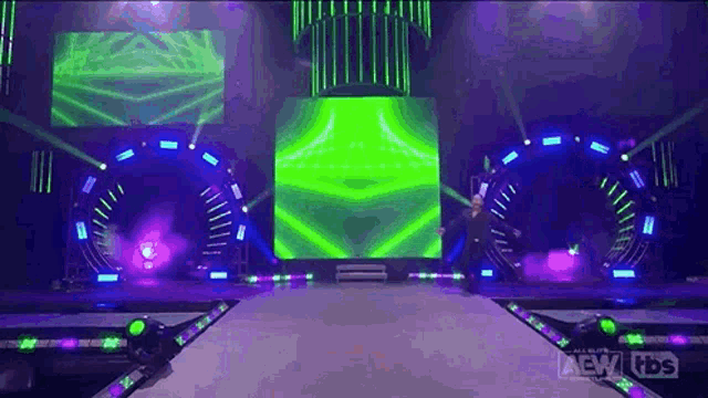 a man is standing on a stage in front of a green and purple screen .