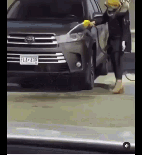 a woman is washing a car with a yellow cloth
