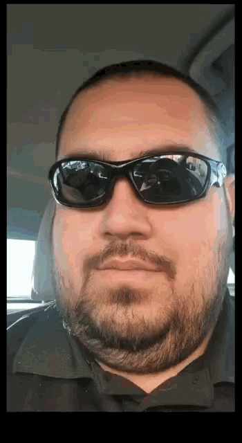 a man with a beard is wearing sunglasses and looking at the camera