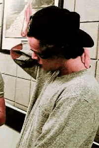 a man wearing a black hat and a grey shirt looks down