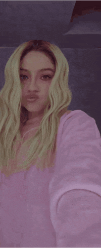 a woman with blonde hair is wearing a pink shirt