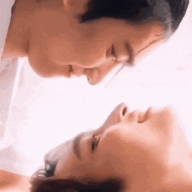 a man and a woman are looking at each other with their faces turned towards each other .