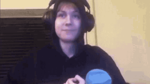 a woman wearing headphones and a hoodie is sitting at a table .
