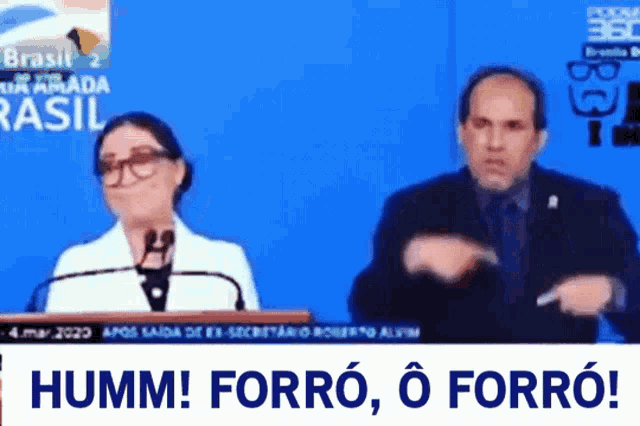 a woman speaking into a microphone next to a man in a suit