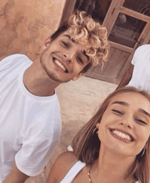 a man and a woman are posing for a picture together and smiling for the camera .