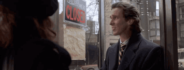 a man in a suit and tie is standing in front of a closed sign