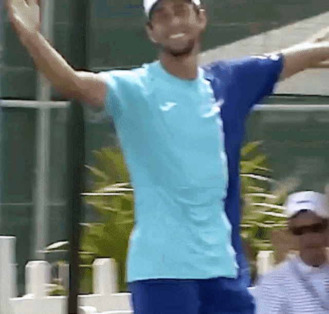 a man in a blue shirt and blue shorts is standing with his arms outstretched