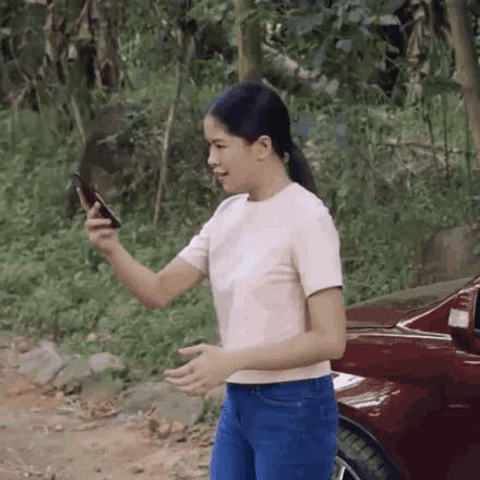 a woman in a pink shirt is looking at her phone
