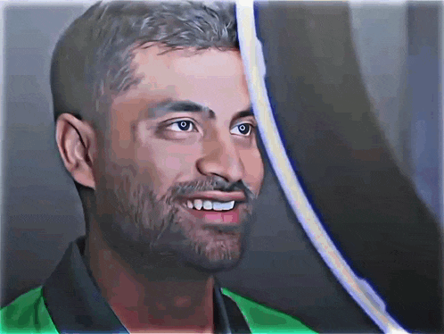 a man with a beard and a green shirt smiles