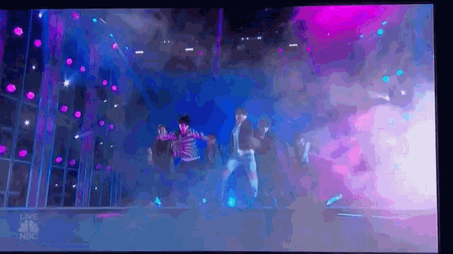 a group of people are dancing on a stage with a lot of lights .