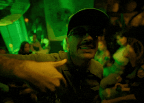 a man wearing sunglasses and a green hat with the letter c on it