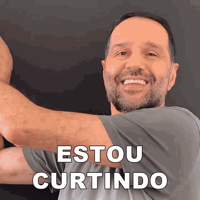 a man with a beard is smiling in front of a sign that says estou curtindo